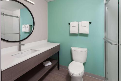 a bathroom with a sink and a toilet and a mirror at ECHO Suites Extended Stay by Wyndham Madison in Madison
