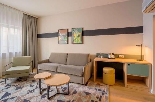 a living room with a couch and a table and chairs at Spark By Hilton Stuttgart Sindelfingen in Sindelfingen