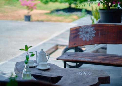 a wooden table with a tea set on it next to a bench at Niyatma Wayanad Pool Resort by VOYE HOMES in Wayanad