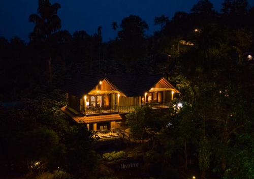 a house with lights on it at night at Niyatma Wayanad Pool Resort by VOYE HOMES in Wayanad