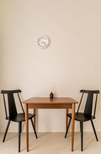 a table with two chairs and a clock on the wall at Flower Base Lily House - Vacation STAY 57830v in Fukuoka