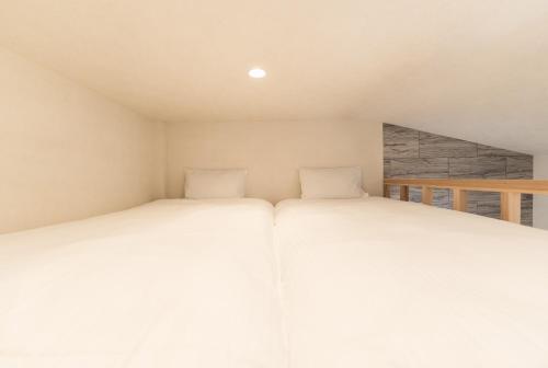 two beds in a small room with white sheets at Flower Base Lily House - Vacation STAY 57830v in Fukuoka