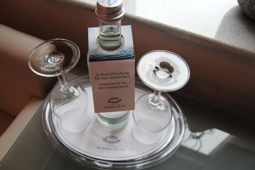 a bottle and glasses sitting on a glass table at Adena Hotel in Bremerhaven