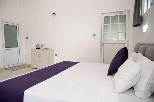 a bedroom with a large bed with purple and white pillows at Liora Homestay in Gelioya