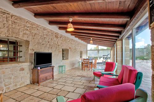 a living room with red chairs and a television at Masseria Pitorre With Pool - Happy Rentals in Conversano