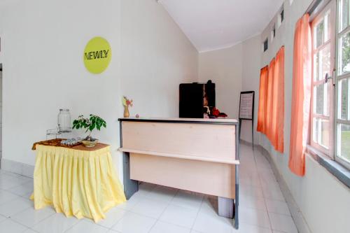 a room with a desk and a table with a yellow skirt at Hotel O Kaliurang Near Gunung Merapi Kaliurang in Yogyakarta