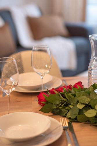 a table with two wine glasses and a plate with flowers at Standing, confort, centre ville,4 personnes in Saint-Étienne