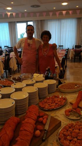 a man and woman standing in front of a table of food at Hotel San Francisco Spiaggia in Rimini