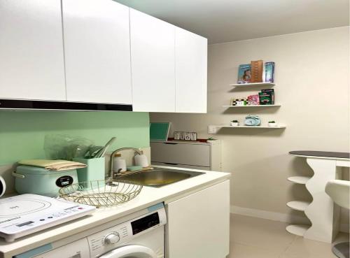 a kitchen with white cabinets and a sink and a dishwasher at Cozy Studio with Balcony and Pool View in Lapu Lapu City