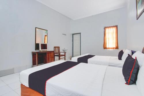 a hotel room with two beds and a television at Hotel O Kaliurang Near Gunung Merapi Kaliurang in Yogyakarta
