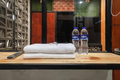 two bottles of water sitting on a table with towels at INNCA Exotic Inn, Semarang in Semarang
