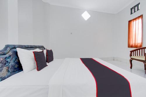 a bedroom with a bed with a red white and blue blanket at Hotel O Kaliurang Near Gunung Merapi Kaliurang in Yogyakarta