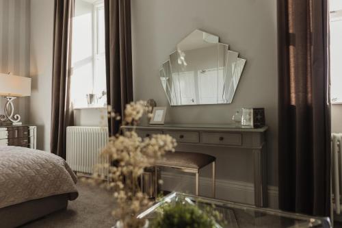 a bedroom with a mirror and a bed and a table at Cartmel Old Grammar in Cartmel
