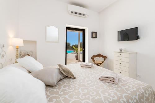 a white bedroom with a large bed and a television at LA CORTE BIANCA LUXURY VILLA in Ostuni