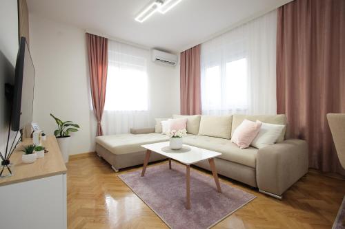 ein Wohnzimmer mit Couch und Tisch in der Unterkunft Apartman Babić Lux in Vrnjačka Banja
