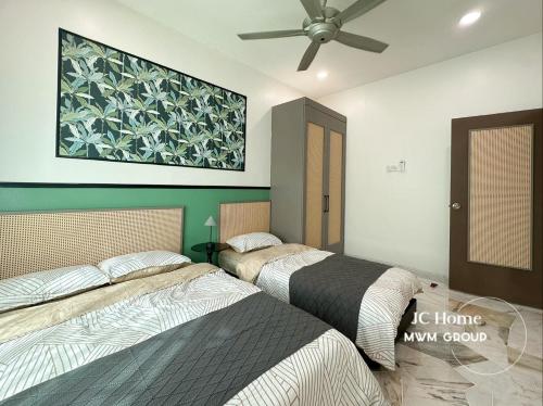 two beds in a bedroom with a ceiling fan at NanYang Style Kluang Holiday Suites in Kluang