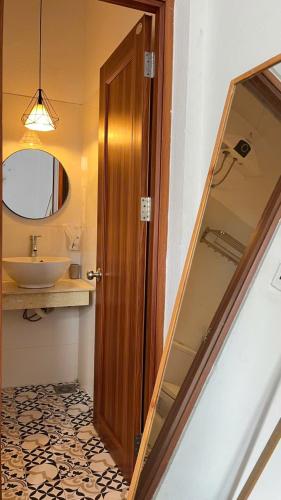 a bathroom with a sink and a wooden door at Vang's Homestay - Huế in Ấp Long Hồ Hạ