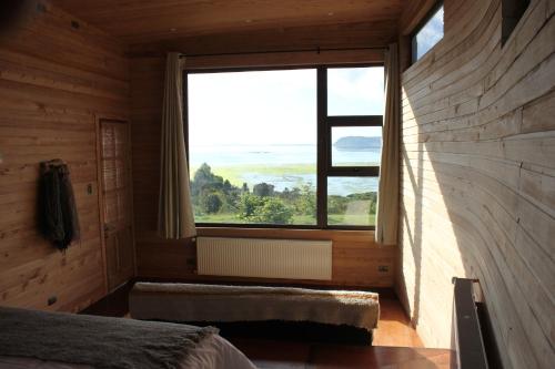 a bedroom with a large window in a wooden house at Refugio Pullao in Quilquico