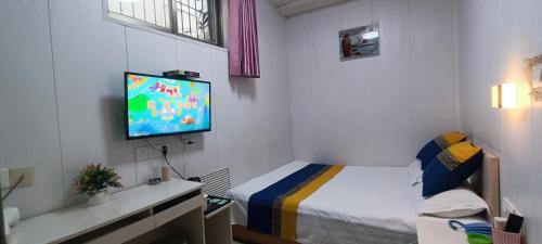 a small bedroom with a bed and a flat screen tv at Qufu Garden Hotel in Qufu