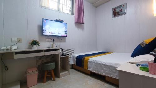 a hotel room with a bed and a tv on the wall at Qufu Garden Hotel in Qufu