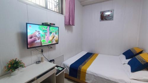 a small room with a bed and a flat screen tv at Qufu Garden Hotel in Qufu