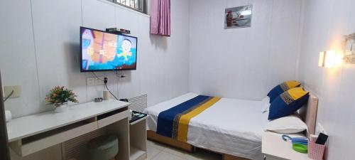 a small bedroom with a bed and a tv on the wall at Qufu Garden Hotel in Qufu