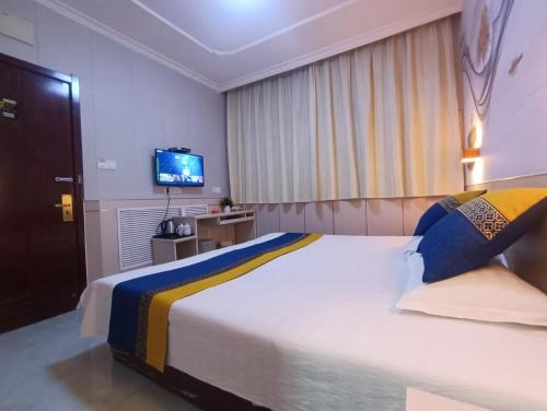a bedroom with a large bed and a television at Qufu Garden Hotel in Qufu