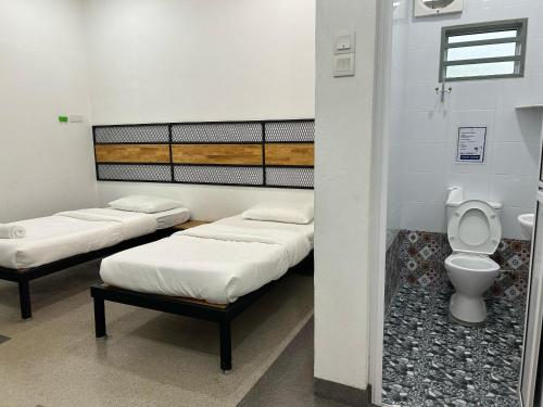 une chambre avec trois lits et des toilettes dans l'établissement Warm Stay No10 Boutique Residence House 7B7B by Verve, à Ipoh