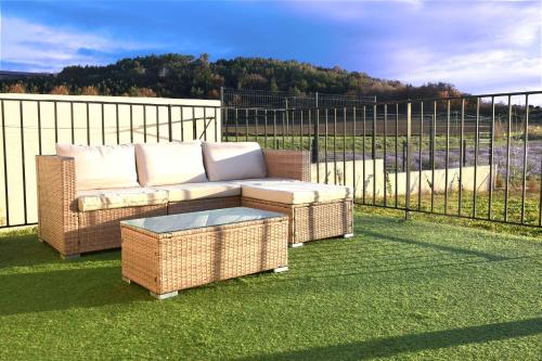 d'un canapé en osier et d'une table sur un balcon. dans l'établissement Havre de Paix et Lavandes - Très Calme - Salle de jeux - Jacuzzi Chauffé - Idéalement placée - Aucun vis à vis, à Savasse