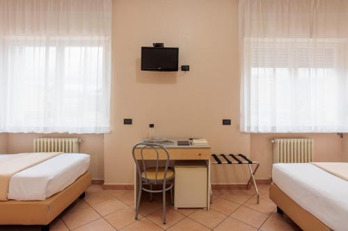 a room with two beds and a desk and a tv at Al Centro in Verbania