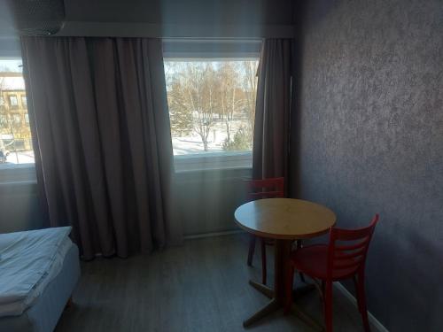 a room with a table and a bed and a window at Hostel Kulma in Lieksa