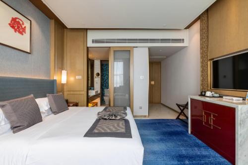 a hotel room with a large bed and a flat screen tv at Bliss International Hotel in Weihai