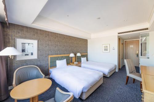 a hotel room with two beds and a table and chairs at The QUBE Hotel Chiba in Chiba
