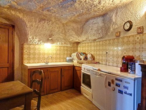 Il comprend une cuisine équipée d'une cuisinière blanche et d'un évier. dans l'établissement Maison semi troglodyte, à Bourré