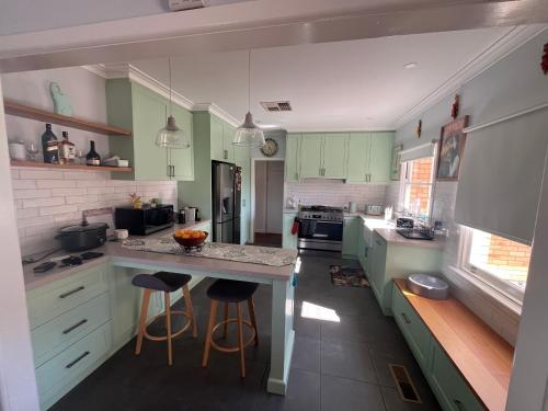 a kitchen with green cabinets and a island with bar stools at The Ashlyn Retreat Shepparton in Shepparton