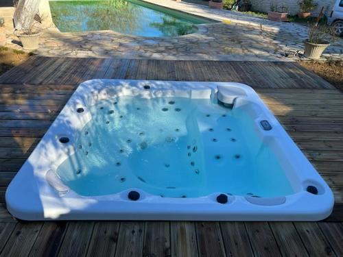 a bath tub sitting on top of a wooden deck at Domaine du Bilé - Piscine et Jacuzzi privés in Solomiac