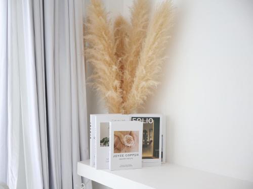 a shelf with two books and a feather vase at MoonE in Ban Karon