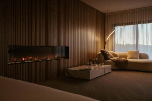 a living room with a couch and a fireplace at Amarè Beachside Luxury in Turners Beach