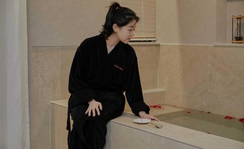 a woman sitting on a ledge in a bath room at StayPassport Morocco Spa Incheon Songdo in Incheon