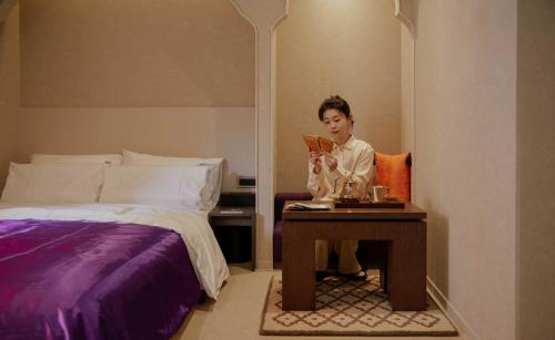 a woman sitting on a table next to a bed at StayPassport Morocco Spa Incheon Songdo in Incheon