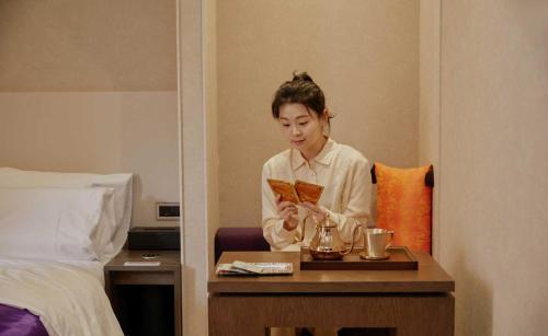 a woman sitting at a table in a hotel room at StayPassport Morocco Spa Incheon Songdo in Incheon