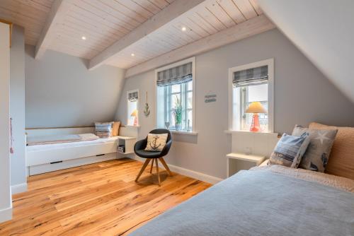 Un dormitorio con una cama, un escritorio y una silla. en FriesenLodge, en Utersum