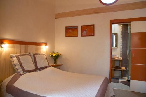 - une chambre avec un lit et un vase de fleurs dans l'établissement Le Petit Saint-Julien, à Saint-Julien-les-Villas
