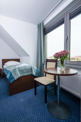 a hotel room with a bed and a table with flowers on it at Marina Wolin in Wolin