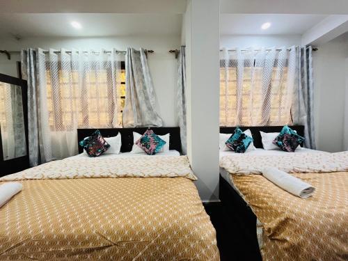 two beds in a room with two windows at shalom inn home stay in Darjeeling