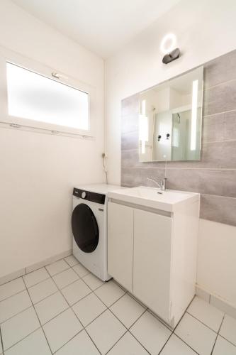 une salle de bain blanche avec une machine à laver et un lavabo dans l'établissement T3 tout confort , plage à pied, Garage privé, à Dinard