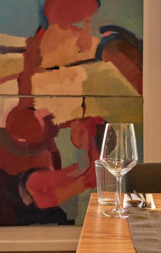 a wine glass sitting on a table next to a painting at apartHotel Sobieskiego 9 in Rybnik