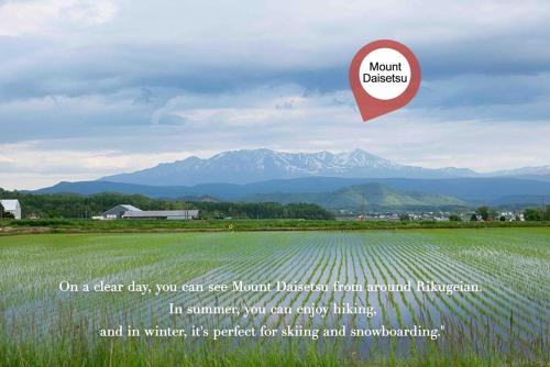 a sign over a field with mountains in the background at A traditional Japanese house with a sunken fireplace, located near Pippu Ski Resort in Pippu