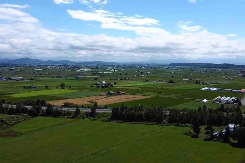 an aerial view of a green field with farms at A traditional Japanese house with a sunken fireplace, located near Pippu Ski Resort in Pippu