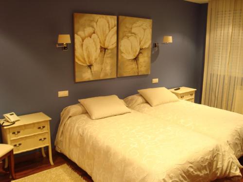 a bedroom with a bed and two paintings on the wall at Hotel San Antonio in Avila